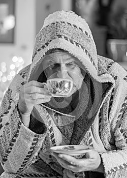 Black and white photo of a man in a robe drinking tea after a bath, portrait of a man