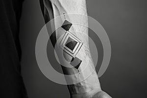 Black and white photo of a mans arm showcasing a geometric tattoo design, A minimalist black and white geometric design on the