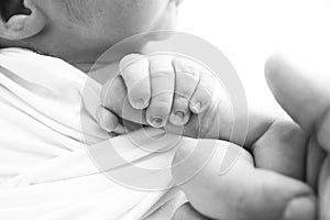 Black and white Photo of Newborn baby after birth tightly holding parents finger