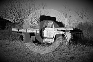 Black and white photo of an old broken down truck.