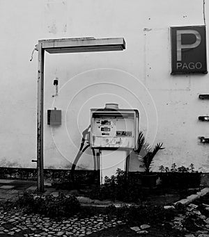 Black and white photo. An old gas station in an abandoned parking lot.