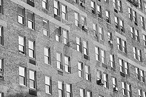 A black and white photo of an old residential building with brick facade and windows, New York City, USA