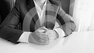 Black and white image of politician in suit sitting in office behind desk