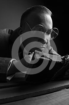 Black and white photo. Portrait of a man.A comical, humorous, cheerful guy in a brown suit and glasses, holding a book