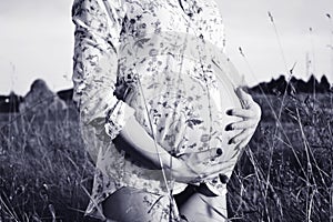 Black and white photo of pregnant woman hugging her belly