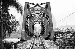 A black and white photo of a railway track on a steel bridge in Taling Chan district, Bangkok.