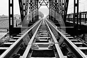 A black and white photo of a railway track on a steel bridge in Taling Chan district, Bangkok.
