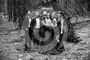 Black-and-white photo in retro style.the couple and the witnesses in the background of a hut in the woods