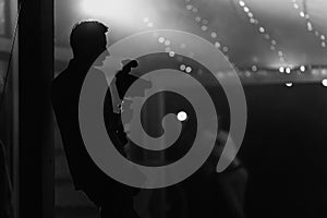 black white photo. Silhouette of cameraman standing with video action film production digital camera at wedding