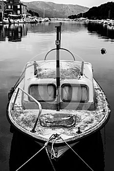 Black and white photo of a small and old boat in Hvar harbor, Croatia.