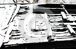 Black and white photo snowy abandoned burned-out fire wooden house.