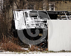 Black and white photo snowy abandoned burned-out fire wooden house.