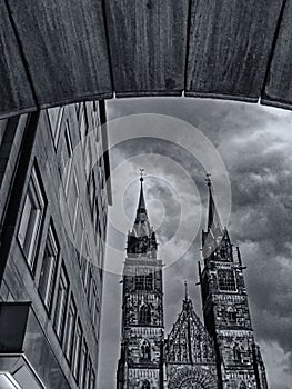Black and white photo of St. Lorenz church in the old town of Nuremberg seen through the arch of a building, Germany