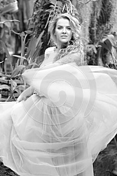 Black and white photo of a stunning girl in a wedding dress, blonde with long curls circling in nature