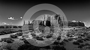 Black and White Photo of the Three Sisters and Mitchell Mesa, a few of the many Red Sandstone Buttes and Mesas in Monument Valley