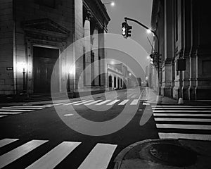 Black and white photo of traffic lights in an empty street and road