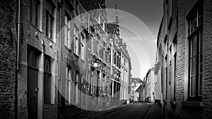 Black and White Photo of a Typical cobblestone street with brick houses in the historic city of Bruges