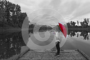 Black & White photo of woman on a dock with a red umbrella