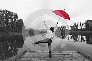 Black and white photo of woman with red umbrella.