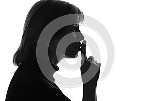 Black and white photo of a woman who had cut his index finger to his lips urging silent