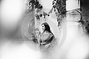 Black and white photo of young woman on autumn street with colorful leaves around. Orange leaves have fallen and are