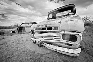 A black and white photograph of an abandoned vintage car wreck photo