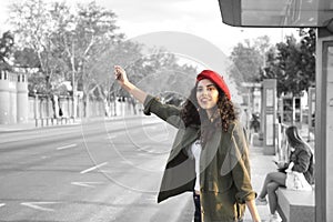 Black and white photograph with color of a young and beautiful woman, brunette, with curly hair, with green jacket and red beret,