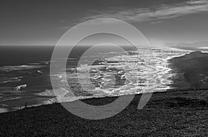 Black and white photograph of a sunrise on the extensive Maule beach. In front of Saavedra Chile port. photo