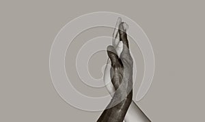 A black-and-white photograph in which black male and white female hands touch palms, intertwining. The concept of interracial