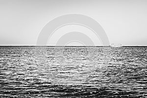 Black-white photography. Alone white boat or ship in silent sea or ocean water