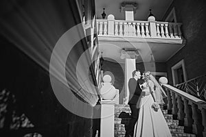 Black white photography bride and groom embracing they stand on background beautiful architecture of the city full length