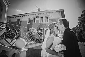 Black white photography bride and groom embracing they stand on background beautiful architecture of the city full length