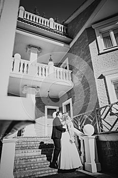 Black white photography bride and groom embracing they stand on background beautiful architecture of the city full length