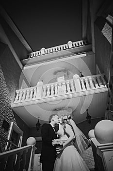 Black white photography bride and groom embracing they stand on background beautiful architecture of the city full length