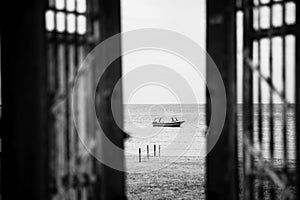 Black-white photography. Doors to alone boat in silent sea or ocean water