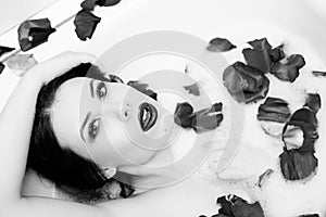 Black white photography of elegant pretty girl with silk skin having fun laying in water bath relaxing