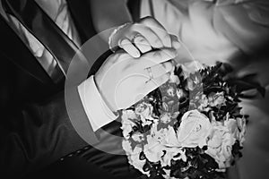 Black white photography hands of bride and groom on the bouquet