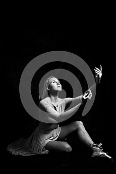 Black and white photography portrait of beautiful young woman in dancing sitting on dark background copy space