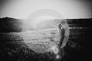 Black white photography romantic couple standing and kissing on background summer field