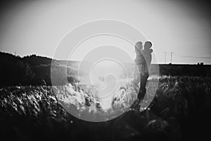 Black white photography romantic couple standing and kissing on background summer meadow