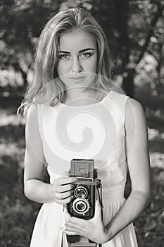 Black white photography of young beautiful blond woman with retro camera in summer nature background