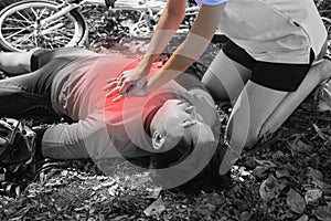 Black and white picture.After Bicycle Race A Cyclist man has Heart Attack or Shock.A woman  give CPR for first aid Cyclist man