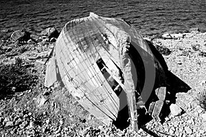 A black and white picture of a broken boat on the coast