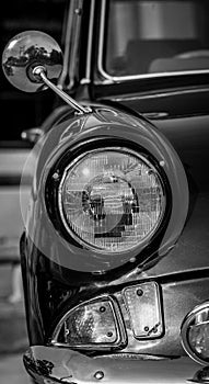 Black and white picture of front view classic car with headlight