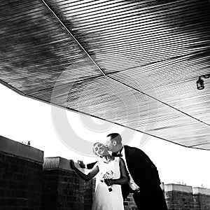 Black and white picture of newlyweds kissing tenderly on the balcony