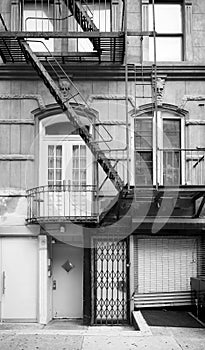 Black and white picture of old building facade with iron fire escape, New York City, USA