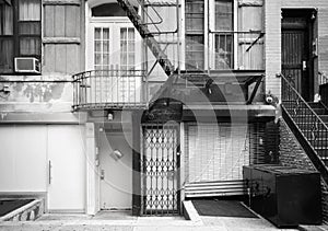 Black and white picture of old building facade with iron fire escape, New York City, USA