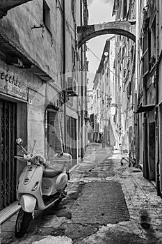 Black White picture of a scooter parked in the narrow street Via Bezzecca in the center of the Italian town San Remo