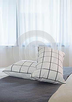 Black and white pillows setting on dark gray bed runner