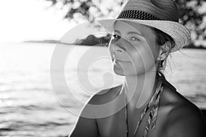 Black and white portrait of an attractive girl in a hat on the beach. Woman on summer vacation on the sea.